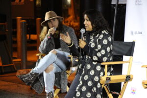 Two filmmakers address the crowd from a stage