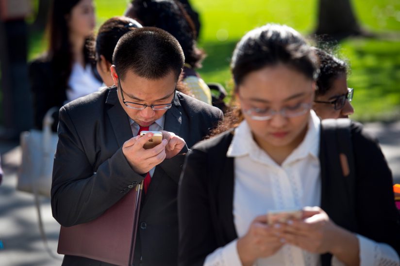 student checking phone while in line.