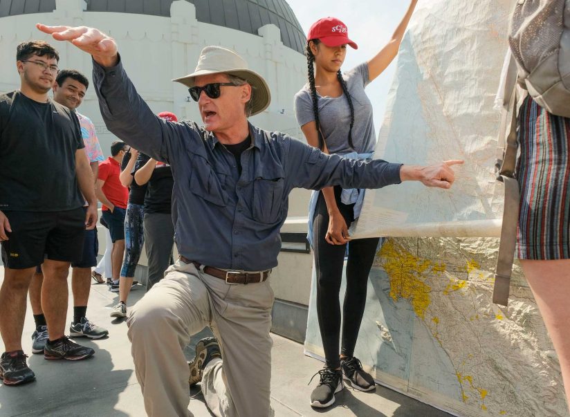 James Dolan pointing at map, kneeling