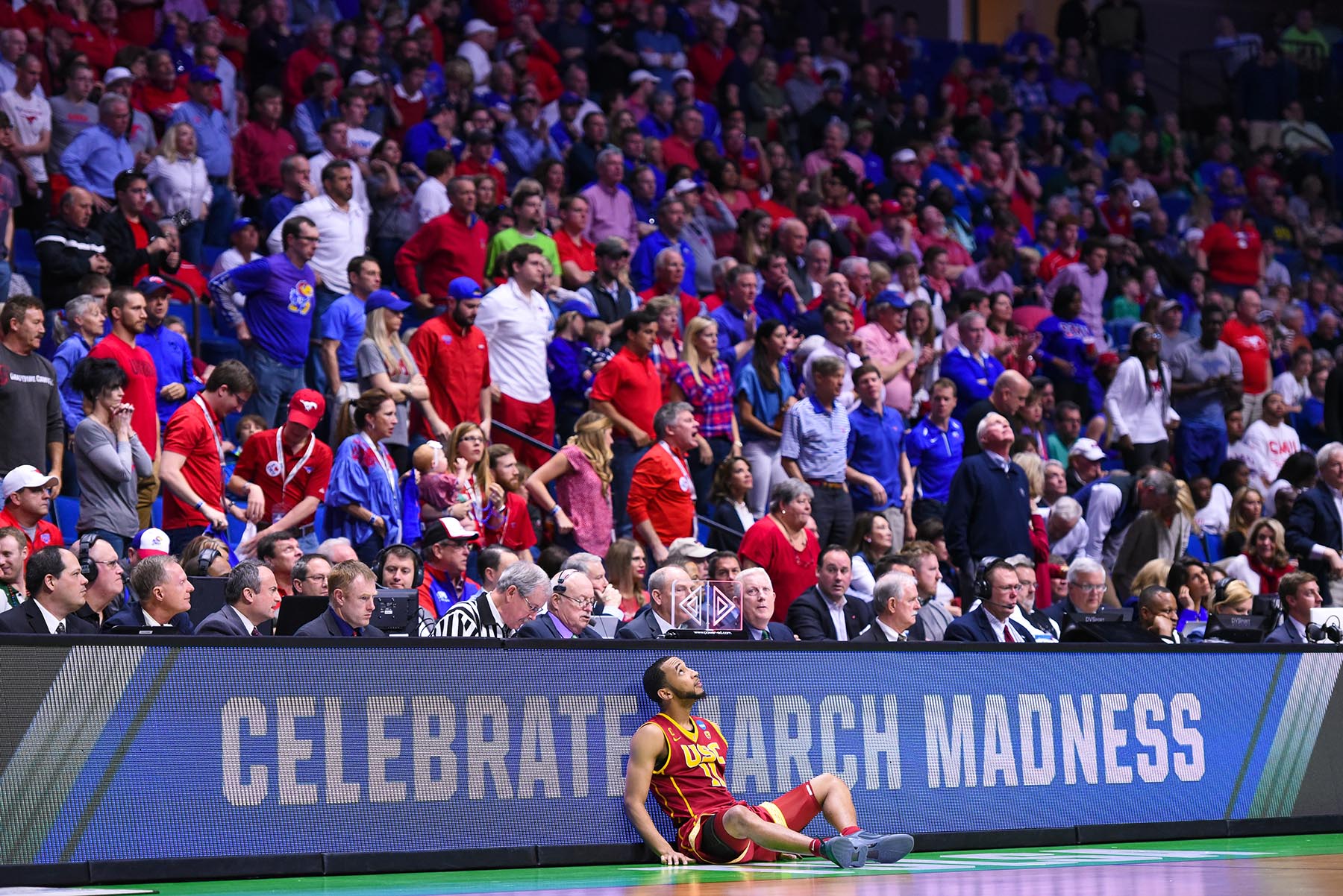 USC basketball player seated against backdrop of fans at SMU game