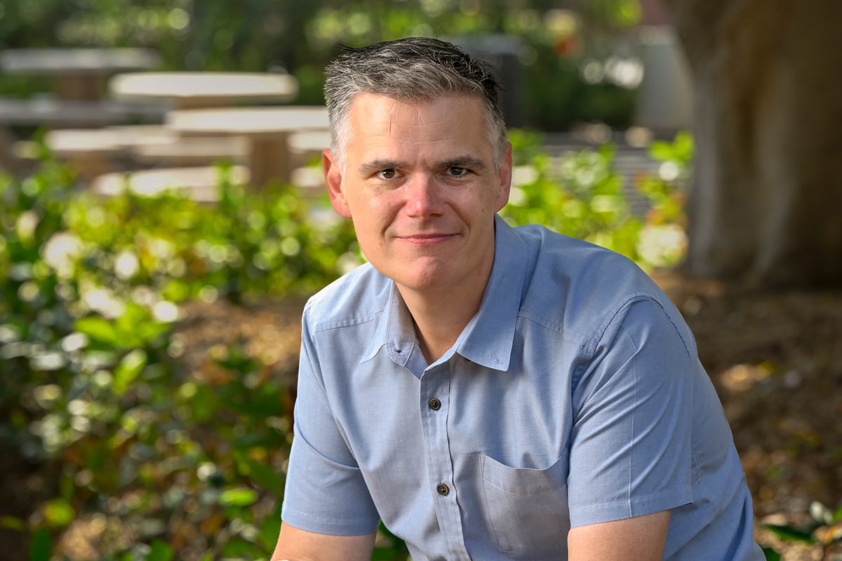 Photo of a man sitting on top of a bench at USC.